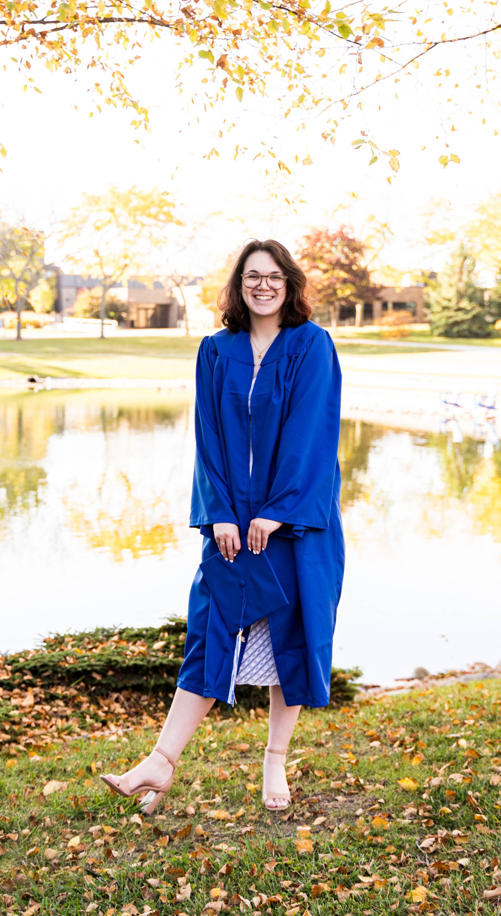 Nichole stands in her graduation robe and smiles at the camera